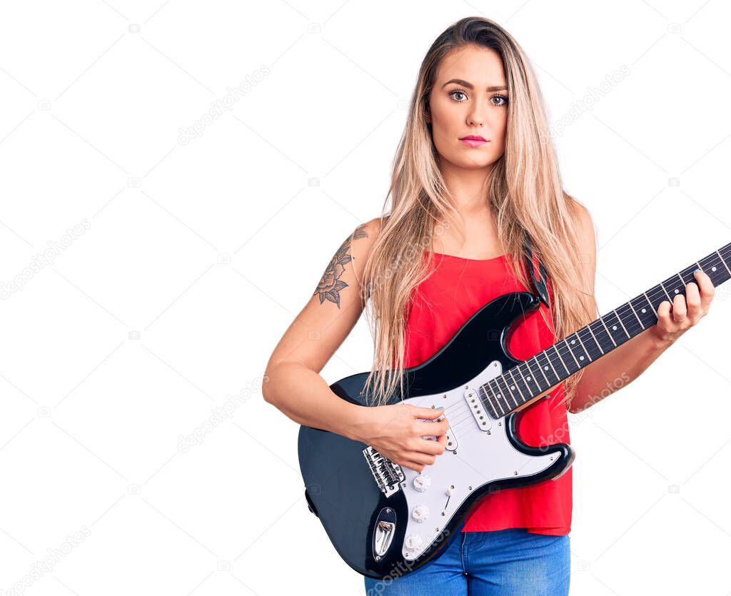 Young beautiful blonde woman playing electric guitar thinking attitude and sober expression looking self confident 