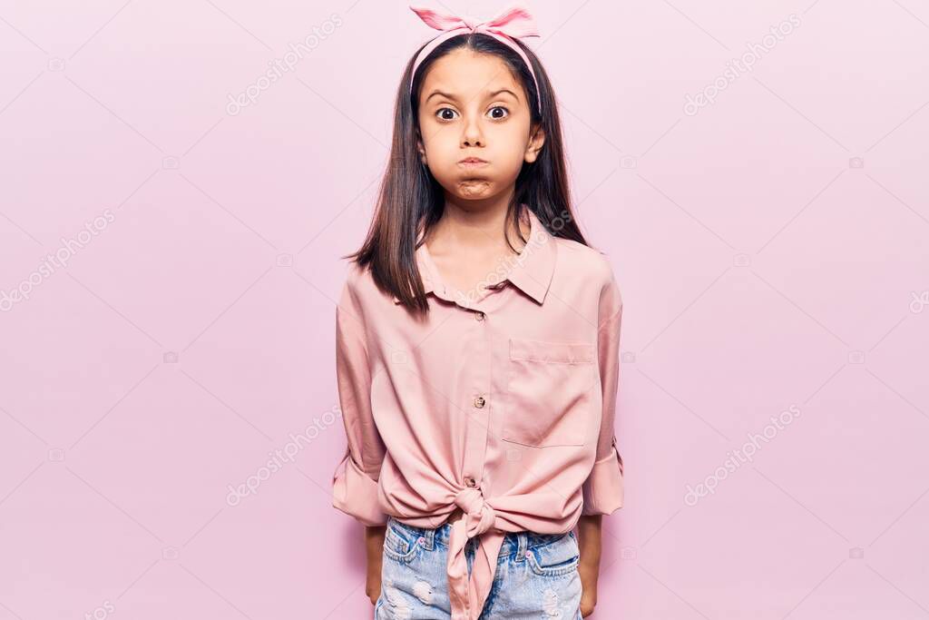 Beautiful child girl wearing casual clothes puffing cheeks with funny face. mouth inflated with air, crazy expression. 