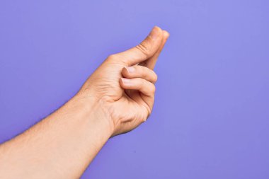 İzole edilmiş mor arka planda parmaklarını gösteren beyaz bir genç adam. Başarı için parmaklarını şıklatıyor, kolay ve elinle sembolü tıklatıyor.