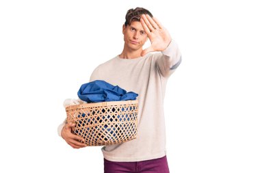 Çamaşır sepetini açık tutan yakışıklı genç adam dur işareti yapıyor. Ciddi ve kendinden emin bir ifadeyle, savunma jesti. 