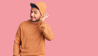 Kış süveteri ve yün şapka giyen yakışıklı Latin Amerikalı genç adam. Kulaktan kulağa gülüyor. Dedikoduları ve dedikoduları dinliyor. Sağırlık kavramı. 