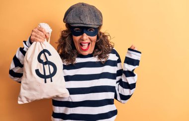 Orta yaşlı esmer hırsız kadın maske takıyor ve yanında dolar sembolü taşıyor gururla bağırıyor, zaferi ve başarıyı kutluyor.