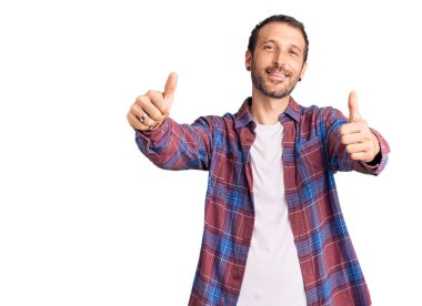 Gündelik giysiler giyen genç bir adam elinle olumlu jest yapıyor, gülümsüyor ve başarı için seviniyor. kazanan jest. 