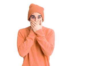 Sakallı, sıradan bir kazak giyen ve yün şapkalı yakışıklı bir adam yanlışlıkla ağzı ellerle kapatmış. gizli kavram. 