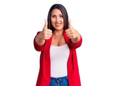 Zarif kıyafetler giyen, zarif giyinen genç ve güzel bir kadın. Elleriyle olumlu bir jest yapıyor. Gülümsüyor ve başarı için seviniyor. kazanan jest. 