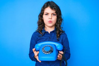 Uzun saçlı, eskimiş telefon tutan, kuşkucu ve gergin, sorun yüzünden suratını asan tatlı İspanyol çocuk. negatif kişi. 