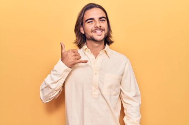 İş kıyafetleri giymiş, gülümseyen, el ve parmaklarıyla telefonla konuşan genç yakışıklı bir adam. iletişim kavramları. 