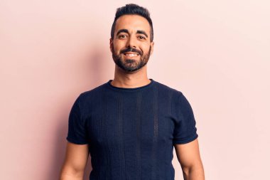 Yüzünde mutlu ve havalı bir gülümseme olan sıradan kıyafetler giyen genç İspanyol bir adam. şanslı kişi. 