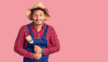 Yakışıklı Latin Amerikalı genç adam. Tamirci üniforması giyiyor. Gülümsüyor ve kahkahalar atıyor.. 