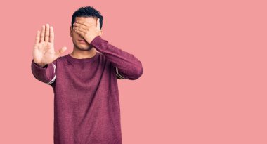 İspanyol asıllı yakışıklı genç adam gündelik kıyafetler giyip elleriyle gözlerini kapatıyor ve üzgün ve korku ifadeleriyle jestleri durduruyor. utangaç ve olumsuz kavram. 