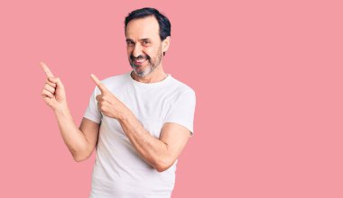 Orta yaşlı, sıradan tişörtler giyen, gülümseyen ve kameraya bakan yakışıklı bir adam.. 