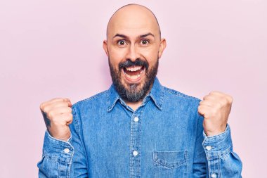 Gündelik giysiler giyen genç yakışıklı adam şaşkınlık ve şaşkınlık içinde kollarını kaldırarak ve gözlerini açarak başarıyı kutluyor. Kazanan konsept. 