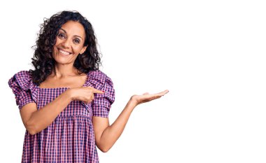 Orta yaşlı, güzel bir kadın, sıradan bir elbise giyiyor. Kameraya hayret ediyor ve gülümsüyor. Elleriyle ve parmağıyla işaret ediyor.. 