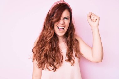 Genç, güzel bir kadın, kızgın ve kızgın. Öfkeyle bağırırken yumruğunu sallıyor ve öfkeleniyor. öfke ve agresif konsept. 