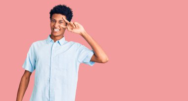 Genç Afro-Amerikan adam günlük kıyafetler giyiyor barış sembolü yapıyor. Yüzünde parmakları var, gülümsüyor ve zaferini gösteriyor. 