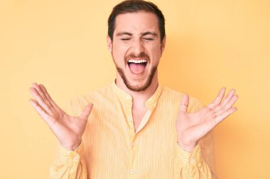 Gündelik kıyafetler giyen genç, çılgın ve çılgın başarıyı kutlayan kollarını kaldırmış, gözlerini kapatmış heyecanlı çığlıklar atan yakışıklı bir adam. Kazanan konsept 