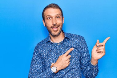 Gündelik kıyafetler giyen, gülümseyen ve kameraya bakan genç, yakışıklı bir adam.. 