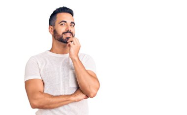 Gündelik kıyafetler giyen genç İspanyol adam kameraya bakıyor kollarını kavuşturup gülümseyerek ve çenesini kaldırarak. Olumlu düşünmek. 