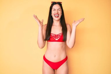 Bikini giyen genç, beyaz bir kadın başarının çılgınlığını kutluyor. Kollarını kaldırmış, gözlerini kapatmış heyecanlı çığlıklar atıyor. Kazanan konsept 