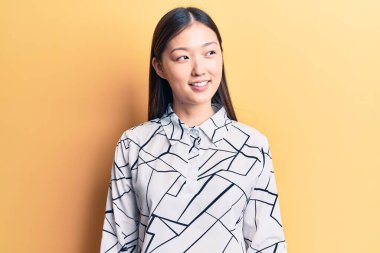 Zarif bir tişört giyen genç, güzel bir Çinli kadın. Taraf arıyor, rahat bir görünüm sergiliyor. Kendine güvenen bir gülümsemeyle.. 