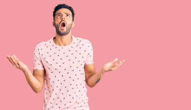 Genç, yakışıklı, sıradan kıyafetler giyen çılgın ve deli gibi bağıran saldırgan bir ifade ve kollarla bağıran bir İspanyol. hüsran kavramı. 