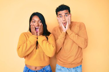 Güzel, Latin, genç bir çift birlikte günlük kıyafetler giyiyorlar. Korkmuş ve şok olmuş, şaşırmış ve şaşırmış görünüyorlar. 