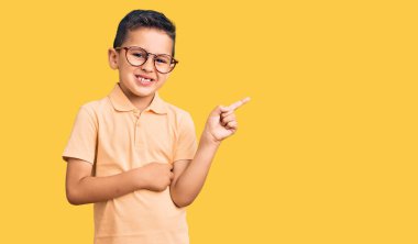 Sıradan kıyafetler ve gözlük takan küçük sevimli çocuk gülümsüyor mutlu bir şekilde elini ve parmağını yana uzatıyordu. 