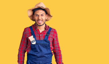 Yakışıklı Latin Amerikalı genç adam tamirci üniforması giyiyor. Dilini komik bir ifadeyle dışarı çıkarıyor. duygu kavramı. 