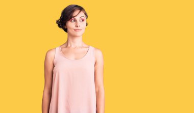 Kısa saçlı, sıradan giyinen, kolsuz tişörtlü, gülümseyen ve düşüncelere dalan güzel bir genç kadın.. 