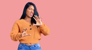 Uzun saçlı İspanyol kadın, günlük kışlık süveter giyiyor. Tiksinti tepkisi yüzünden tiksinmiş ve ürkek bir ifade takınıyor. Eller havada. 