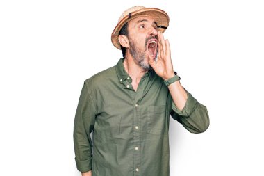 Tatilde olan orta yaşlı bir turist izole edilmiş beyaz arka plan üzerinde kaşif şapkası takıyor ve el ele tutuşarak bağırıyor. İletişim konsepti.