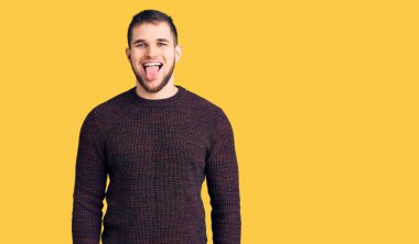 Genç ve yakışıklı bir adam sıradan bir süveter giyiyor. Dilini komik bir ifadeyle dışarı çıkarıyor. duygu kavramı. 