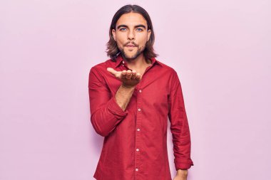 İş kıyafetleri giymiş genç yakışıklı bir adam kameraya bakıyor ve havada bir öpücük savuruyor. Güzel ve seksi. aşk ifadesi. 