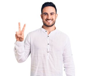 Sıradan kıyafetler giyen, gülen, kameraya göz kırpan, zafer işareti yapan genç yakışıklı bir adam. İki numara.. 