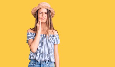 Şapka ve tişört giyen genç güzel bir kız diş ağrısı ya da diş hastalığından dolayı acı dolu bir ifadeyle ağıza dokunuyor. dişçi 