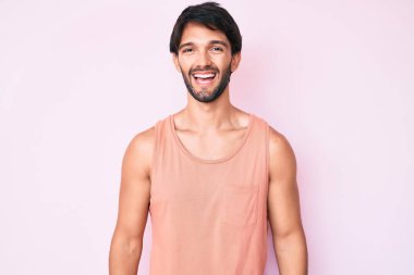 Yakışıklı, sıradan kıyafetler giyen, mutlu ve havalı bir gülümsemesi olan İspanyol bir adam. şanslı kişi. 
