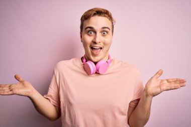 Genç, yakışıklı, kızıl saçlı, pembe arka planda kulaklık takarak müzik dinleyen çılgın ve başarıyı kollarını kaldırıp heyecanla haykıran genç bir adam. Kazanan konsept