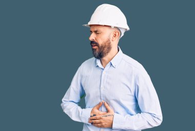 Mimar kasketi takan genç yakışıklı bir adam midesi bulanıyor çünkü mide bulantısı, acı verici bir hastalık kendini iyi hissetmiyor. Ağrı kavramı. 