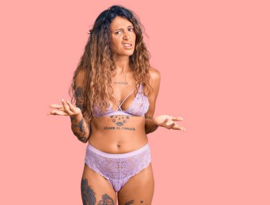 Dövmeli genç İspanyol kadın. İç çamaşırından bihaber ve kolları açık, hiçbir fikri yok.. 