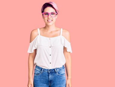 Pembe saçlı, sıradan kıyafetler giyen, mutlu ve havalı bir gülümsemesi olan genç ve güzel bir kadın. şanslı kişi. 