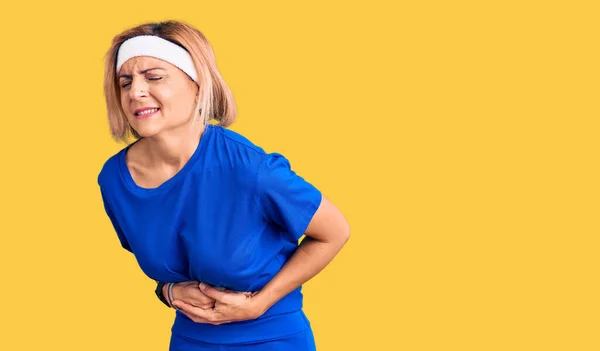 年轻的金发女子穿着运动服 手放在肚子上 因为恶心 痛苦的疾病感觉不舒服 疼痛的概念 — 图库照片