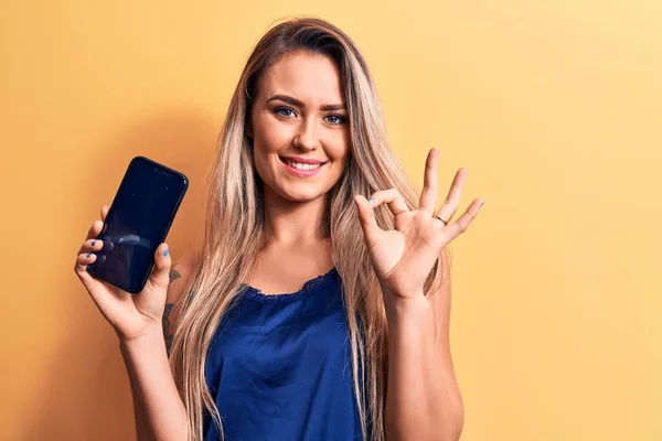 Jovem Bela Mulher Loira Segurando Smartphone Mostrando Tela Sobre Fundo — Fotografia de Stock