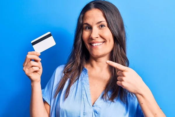 Jovem Bela Morena Segurando Cartão Crédito Sobre Fundo Azul Isolado — Fotografia de Stock