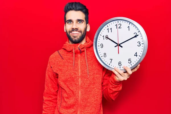 Jovem Homem Bonito Com Barba Segurando Grande Relógio Olhando Positivo — Fotografia de Stock