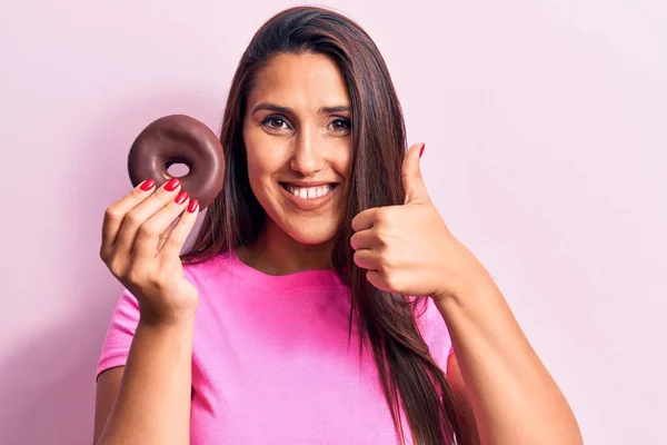 초콜릿 도넛을 행복하고 긍정적 미소를 아름다운 머리의 여성이 훌륭하고 사인을 — 스톡 사진