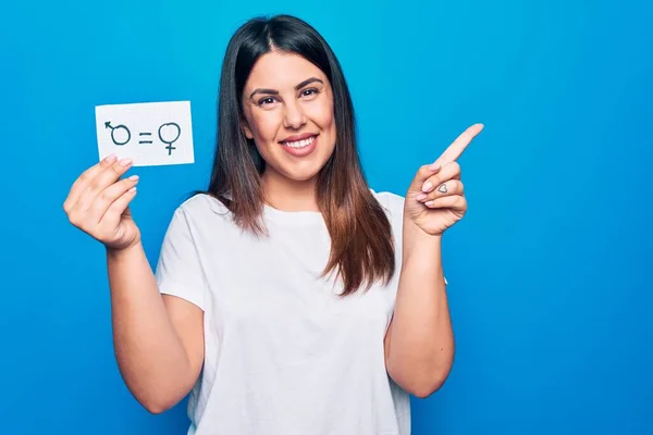 Beautiful woman asking for sex discrimination holding paper with gender equality concept smiling happy pointing with hand and finger to the side