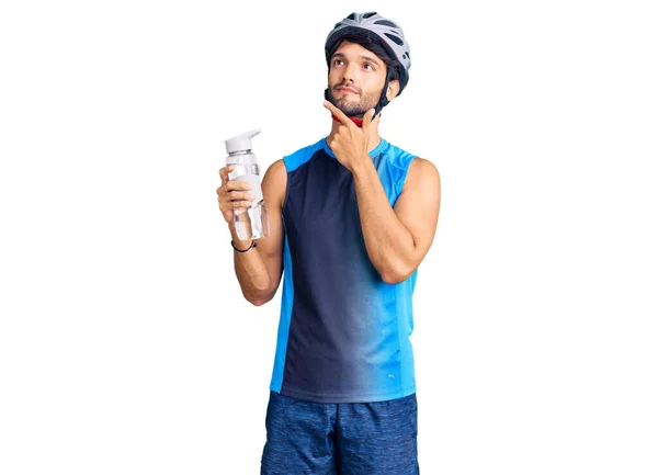 Hombre Hispano Guapo Usando Casco Bicicleta Sosteniendo Cara Seria Botella —  Fotos de Stock