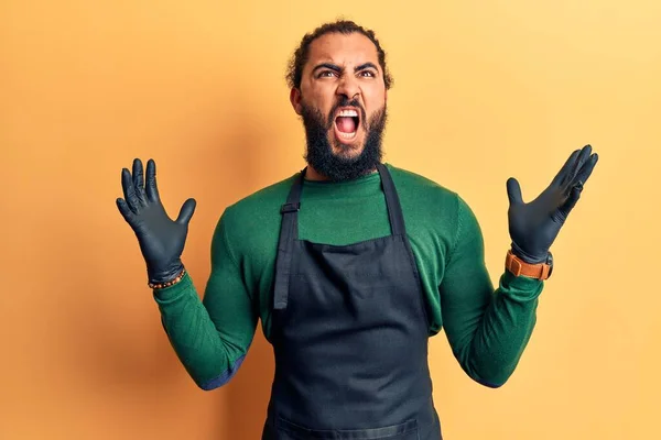 床屋のエプロンを身に着けている若いアラブ人の男は狂気と怒りの叫びと積極的な表現と腕を上げて叫んでいた フラストレーションコンセプト — ストック写真