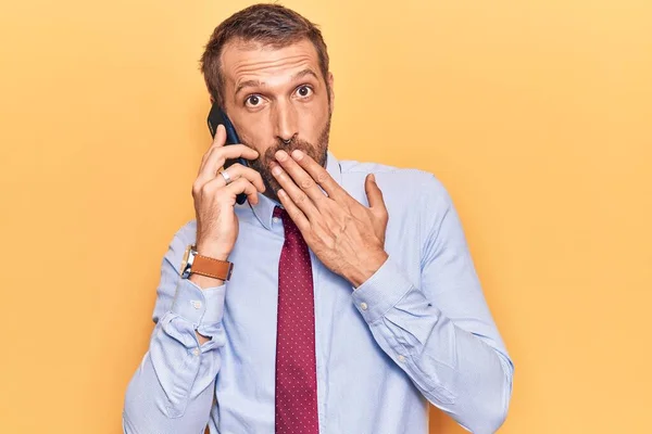 Jovem Homem Bonito Conversando Smartphone Cobrindo Boca Com Mão Chocado — Fotografia de Stock