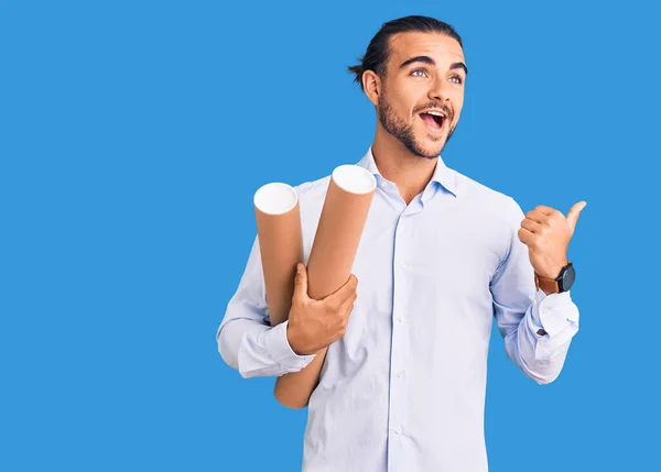 Joven Hombre Guapo Sosteniendo Planos Papel Apuntando Con Pulgar Hacia — Foto de Stock